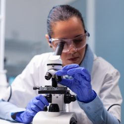 Specialist pharmacist examining bacteriology infection lab test using medical microscope working in pharmacology hospital laboratory. Scientist microbiologist analyzing microbiology expertise